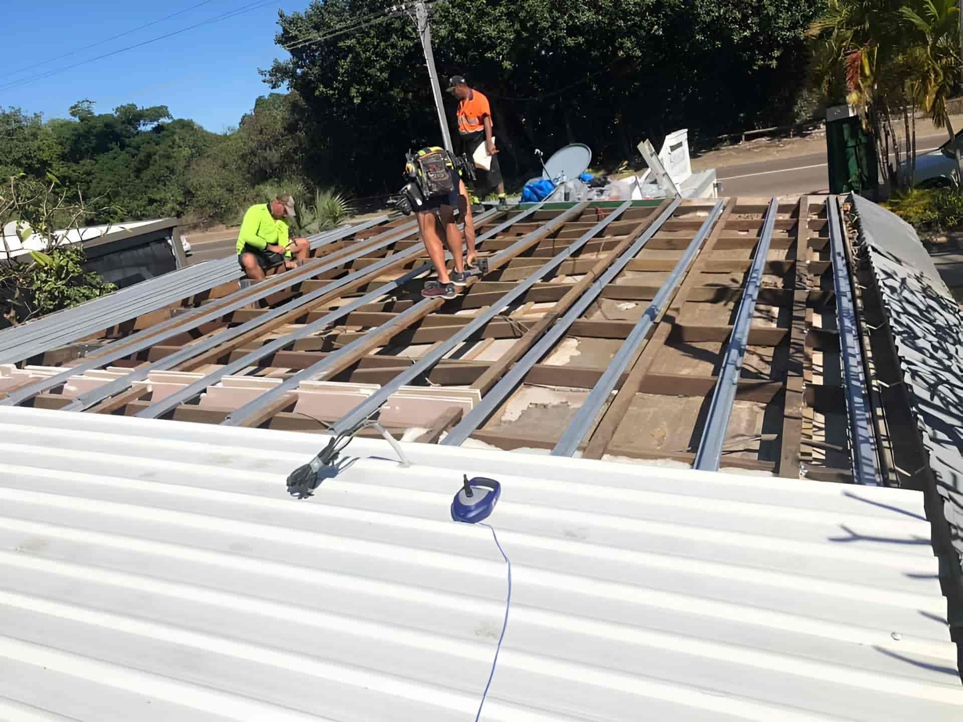 A Group Of Men Are Working On The Roof Of A House — Posty’s Roofing In Proserpine, QLD