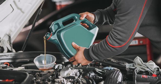 A man is pouring oil into a car engine. A man is pouring oil into a car engine.