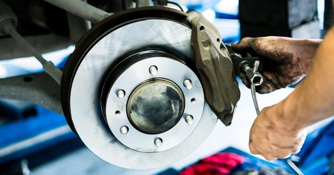 A person is working on a brake disc on a car. A person is working on a brake disc on a car.
