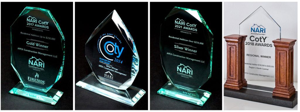 Awards: glass plaques with inscriptions and logo, some with wooden pillars on a black surface.