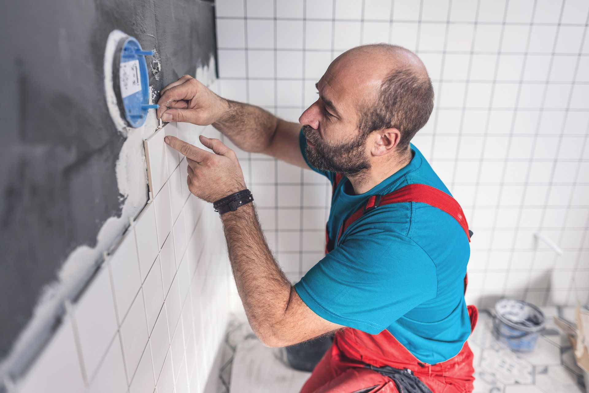 Electrician installing wall socket during bathroom renovation with white ceramic tiles. Electrician installing wall socket during bathroom renovation with white ceramic tiles.