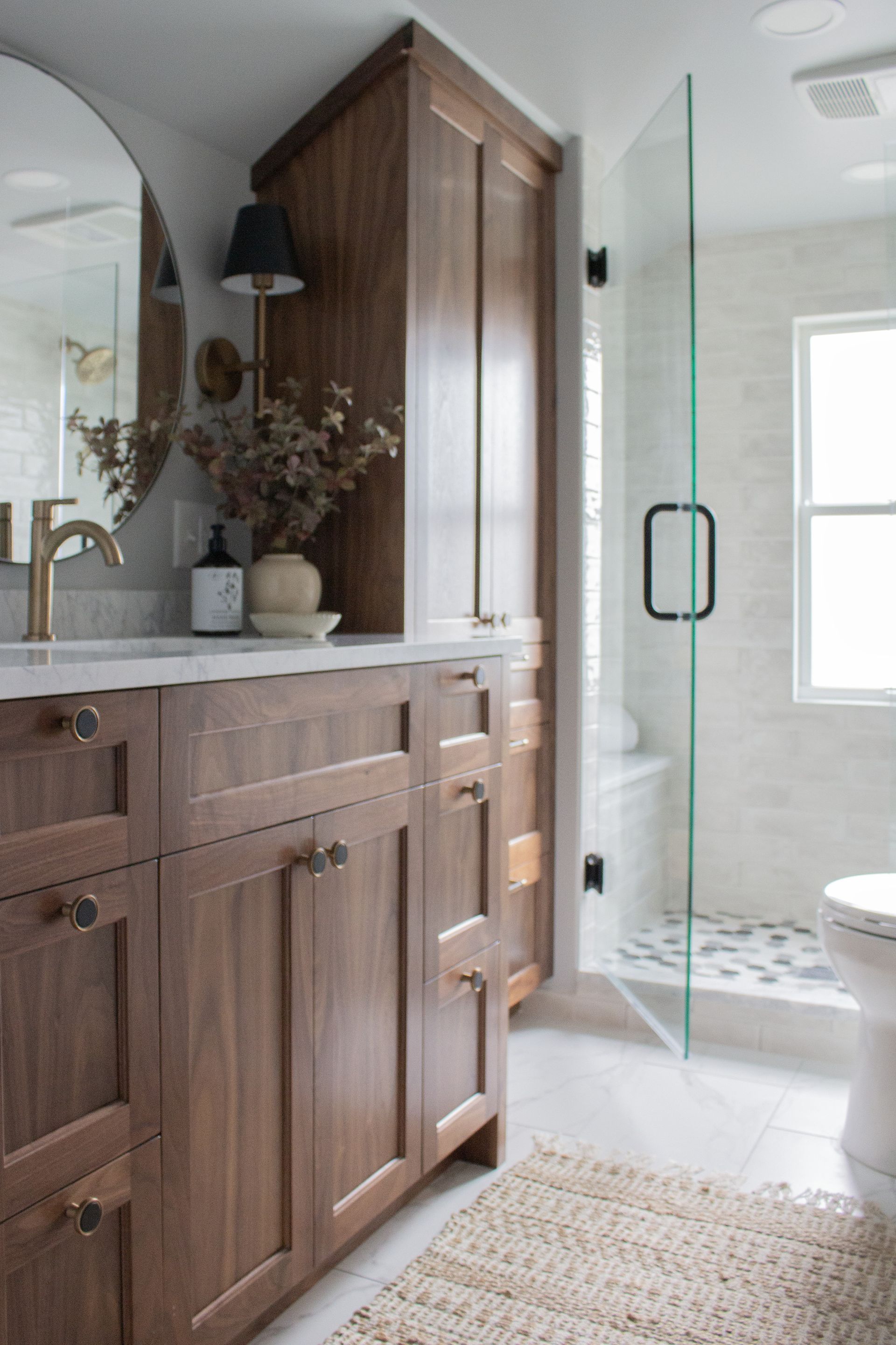St. Paul bathroom remodeling project featuring custom wood cabinetry, frameless glass shower, and modern lighting
