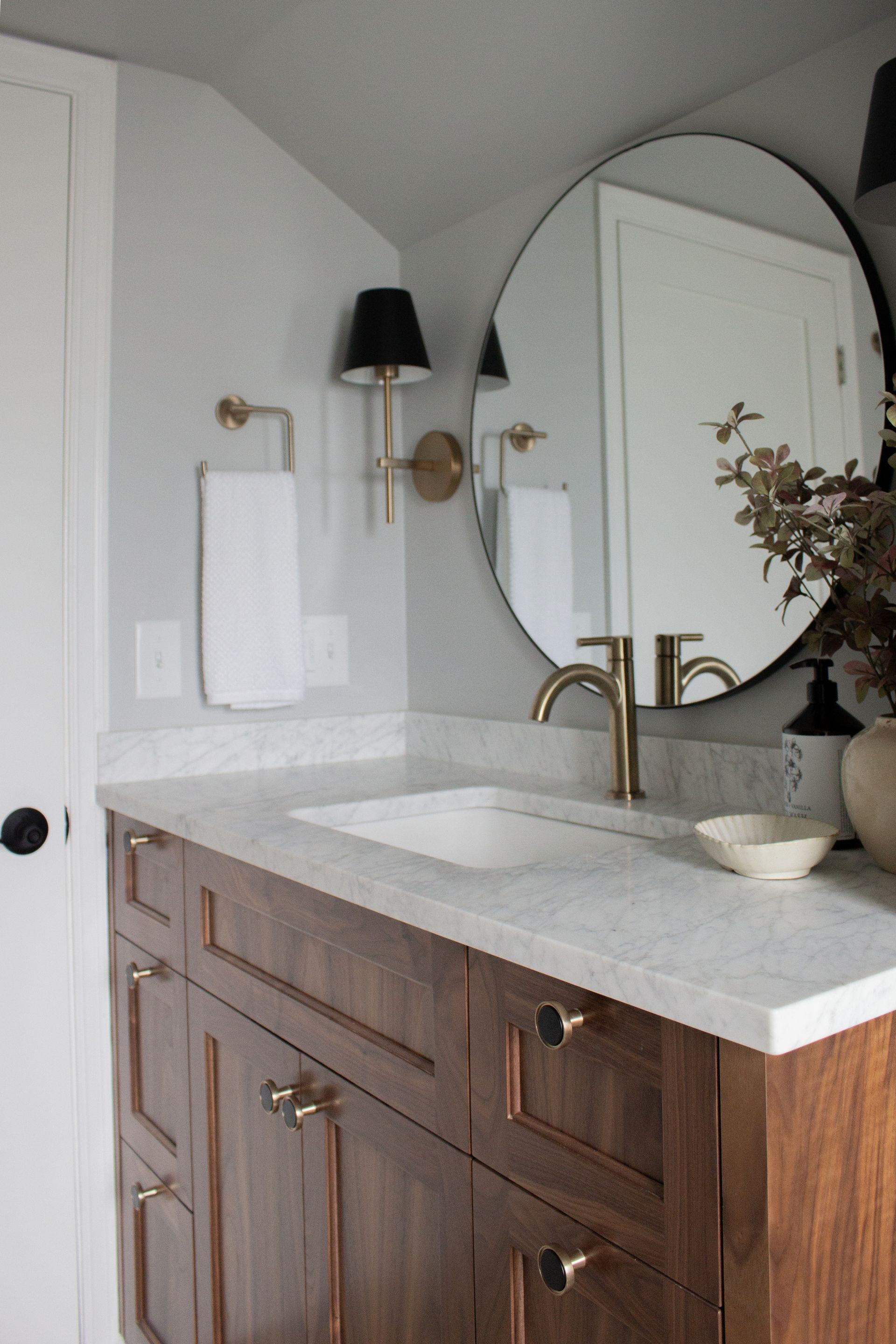 Custom bathroom renovation in St. Paul with arched mirror, designer wall sconces, and updated vanity area
