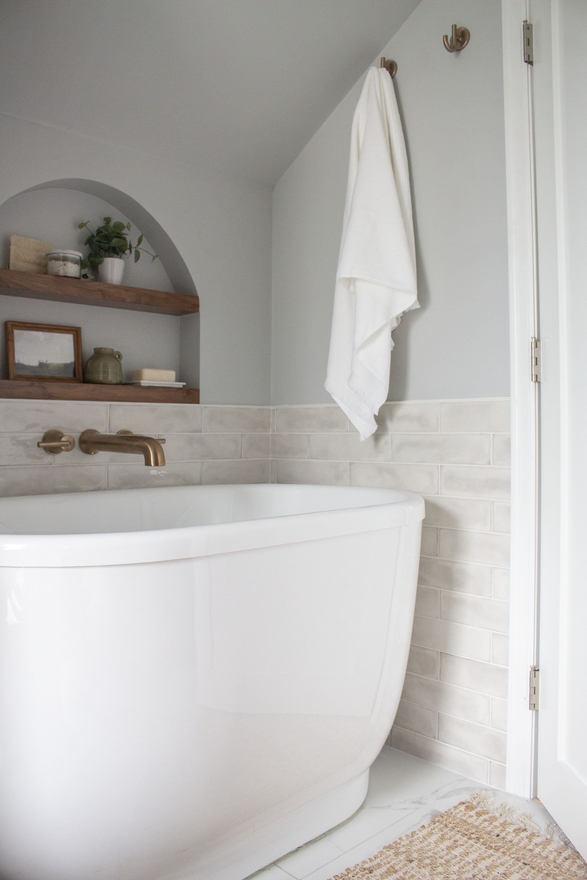 Bathroom remodel in St. Paul, MN showcasing an arched wall niche with wood shelving and decorative storage