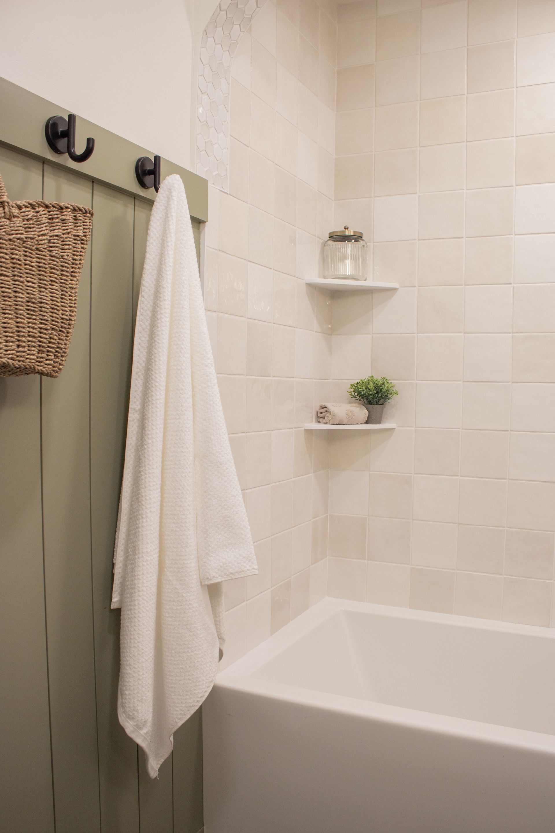 Custom bathroom renovation in St. Paul, MN with tiled shower surround, decorative arch, and built-in corner shelf
