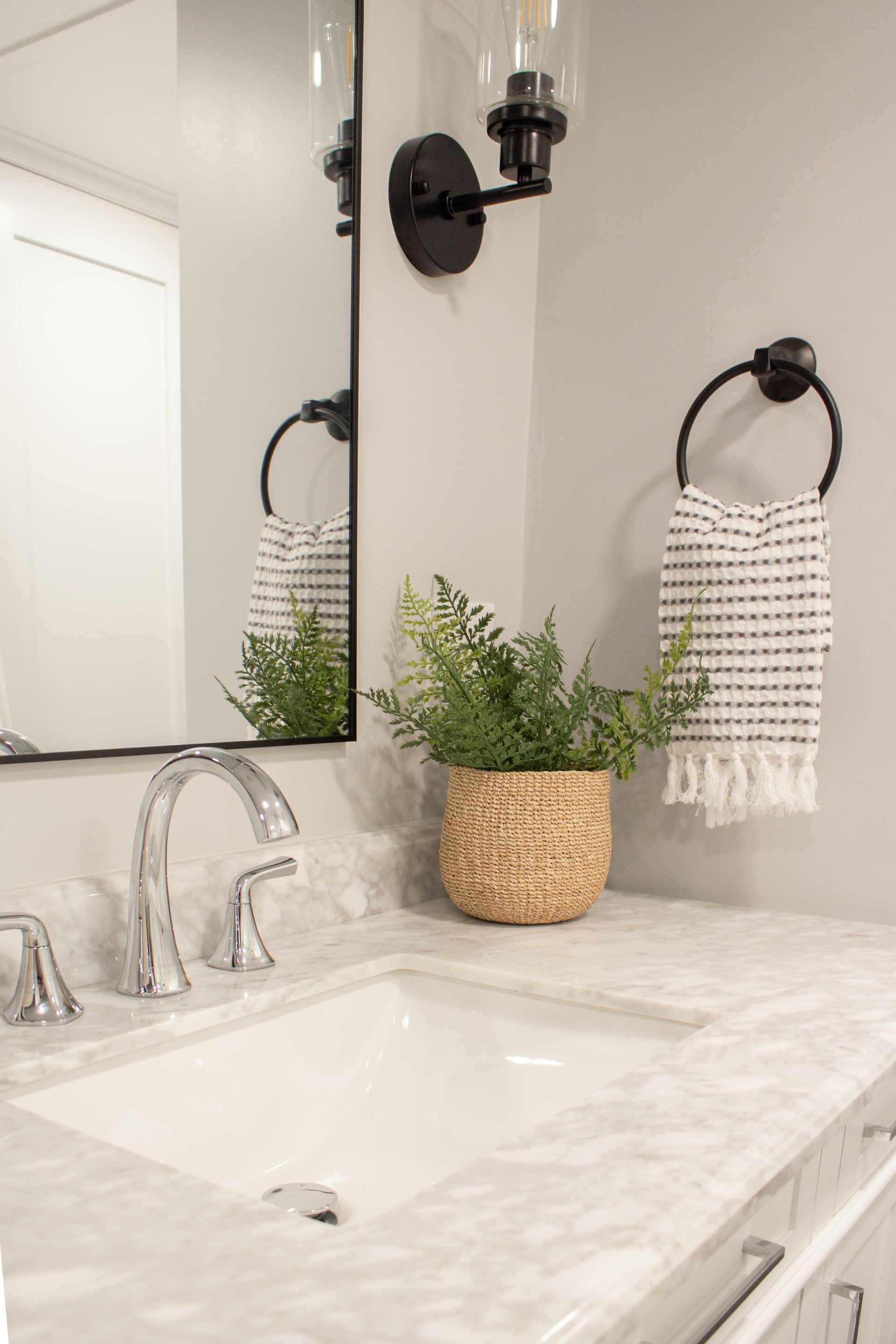 St. Paul bathroom renovation featuring designer vanity lighting, black hardware, and decorative towel ring