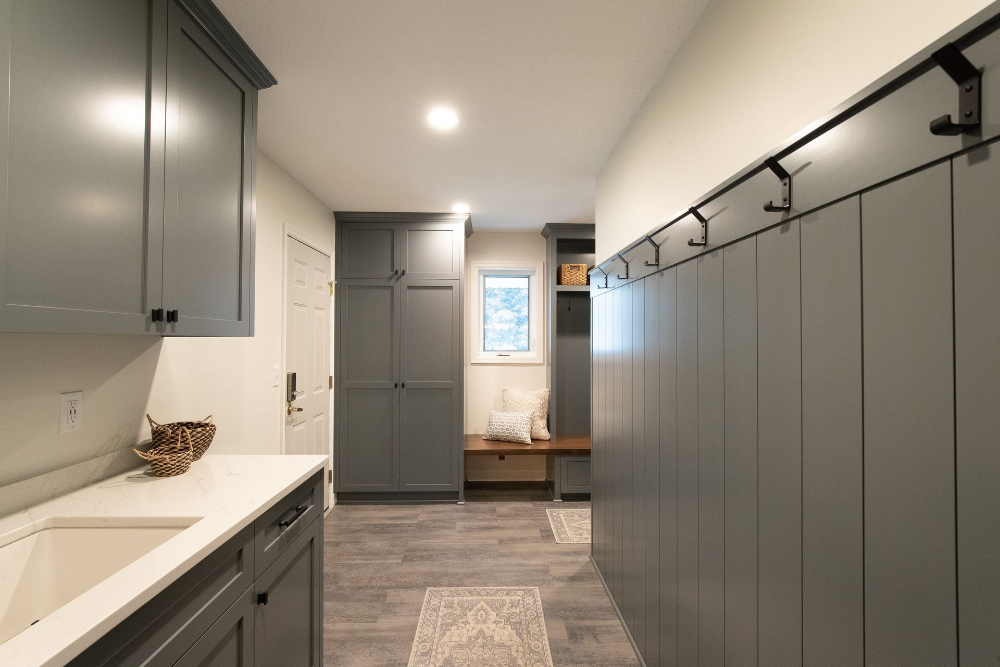 Mudroom with gray cabinets, a sink, and a bench; light wood floor.