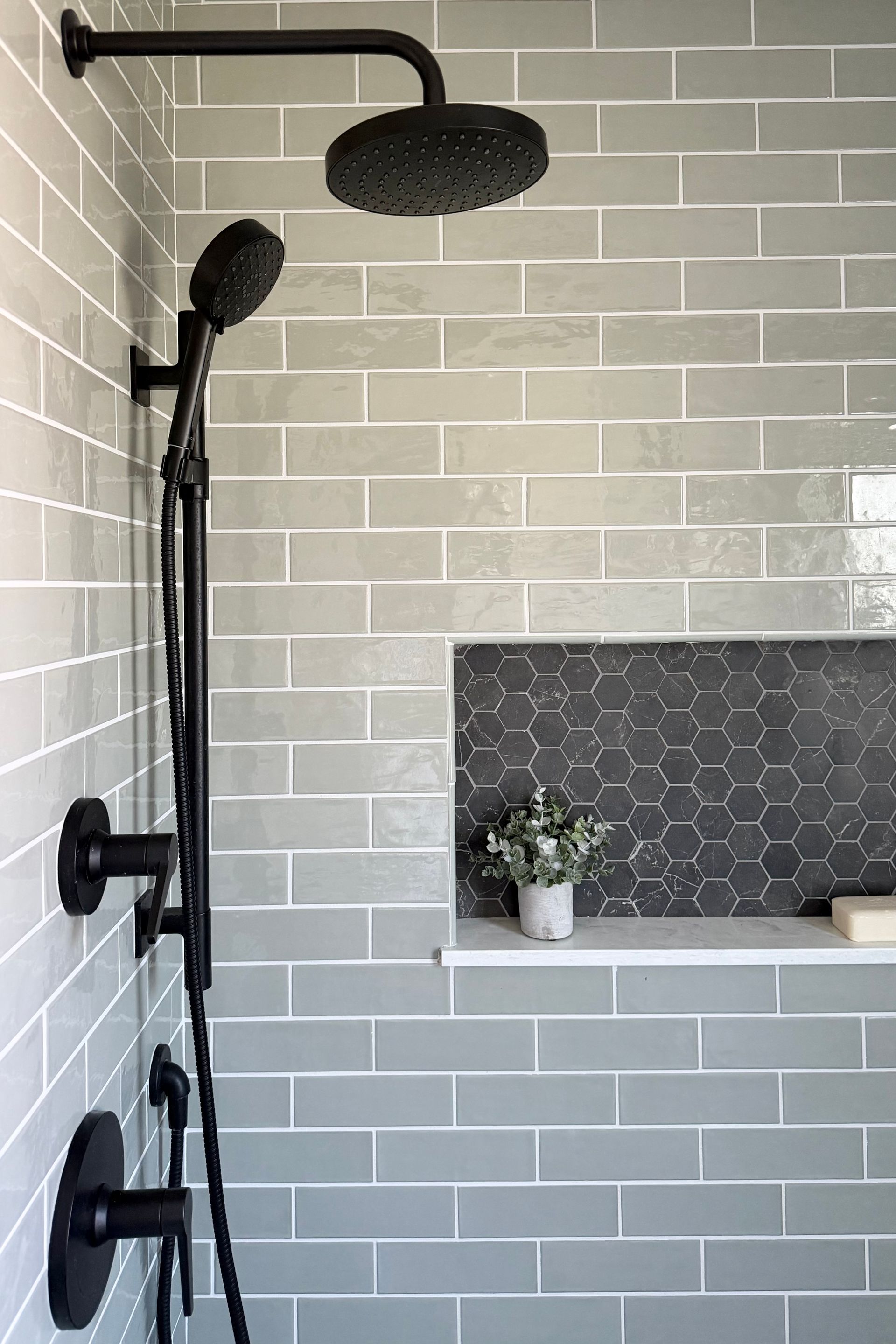 Modern bathroom vanity with white sink, black-framed mirror, gray cabinets, and a towel hanging beside a shower door