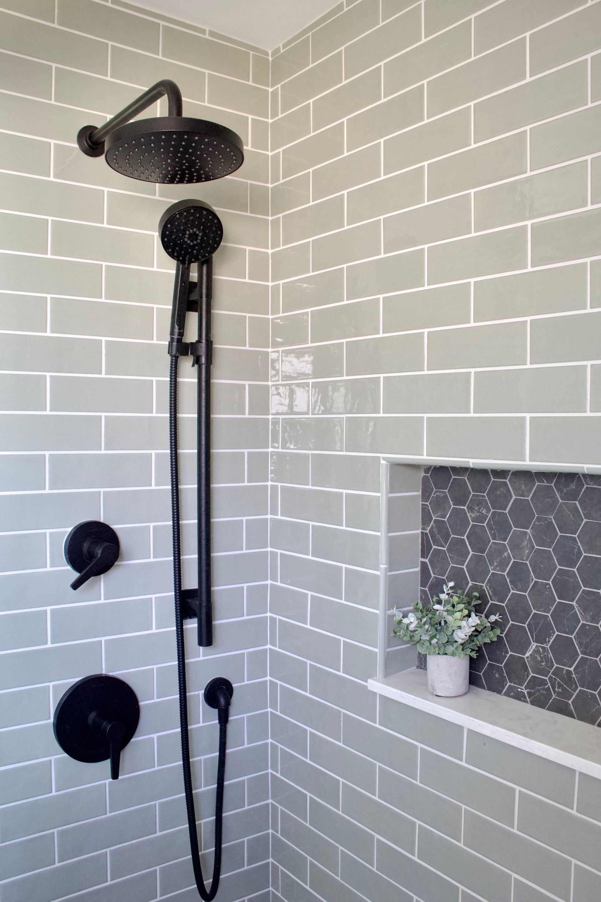 Black shower fixture with handheld sprayer in a gray subway-tile bathroom