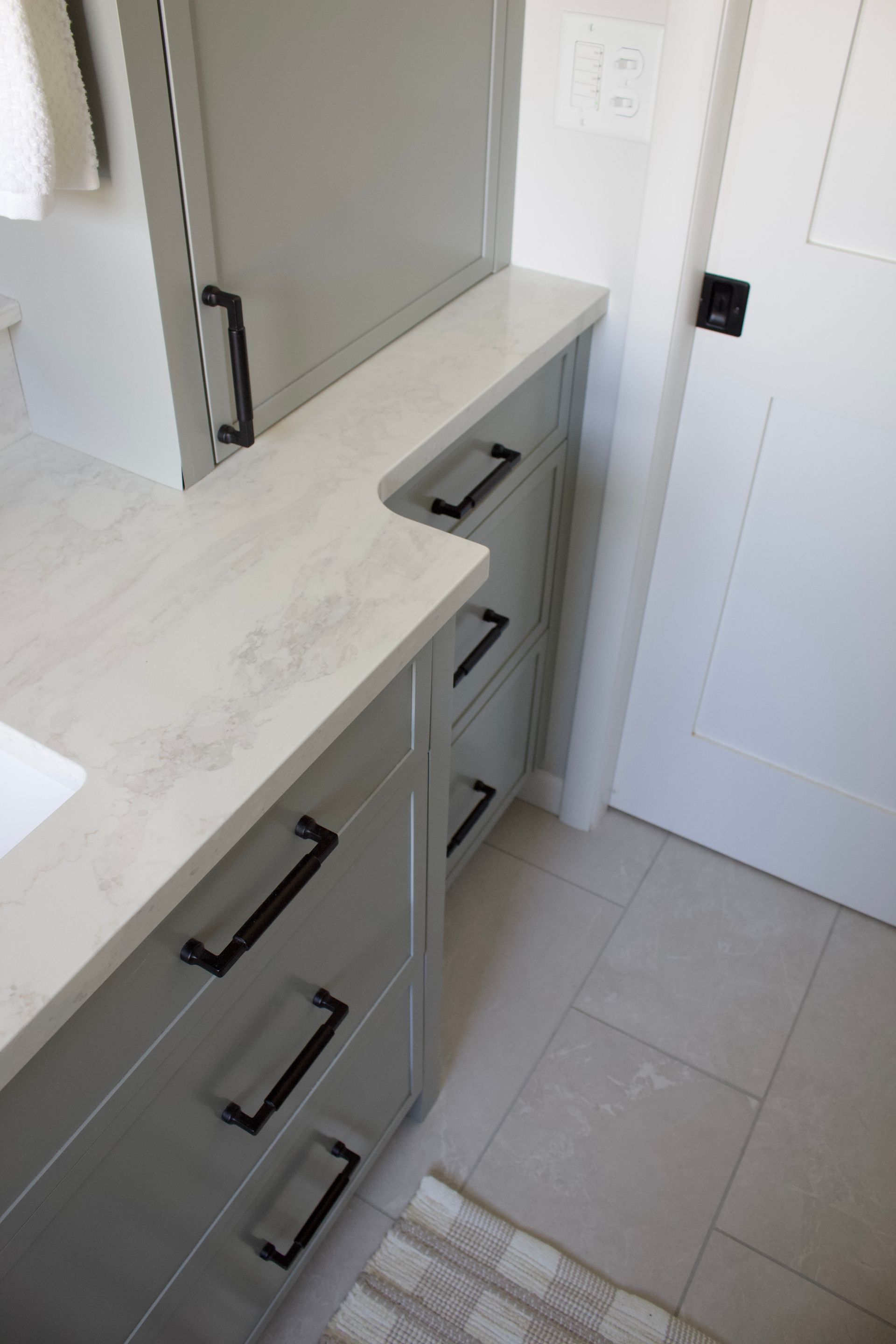 Bathroom vanity with gray drawers, white countertop, mirror, and tiled floor