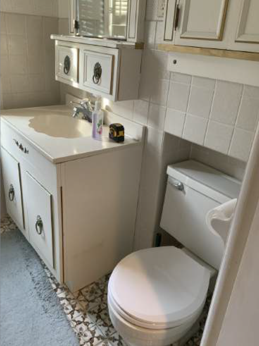 White bathroom with sink, vanity, toilet, and tiled wall.