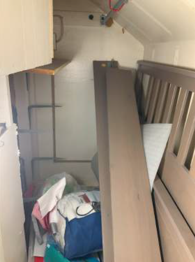 A cluttered closet with a dismantled crib, shelves, and various items.