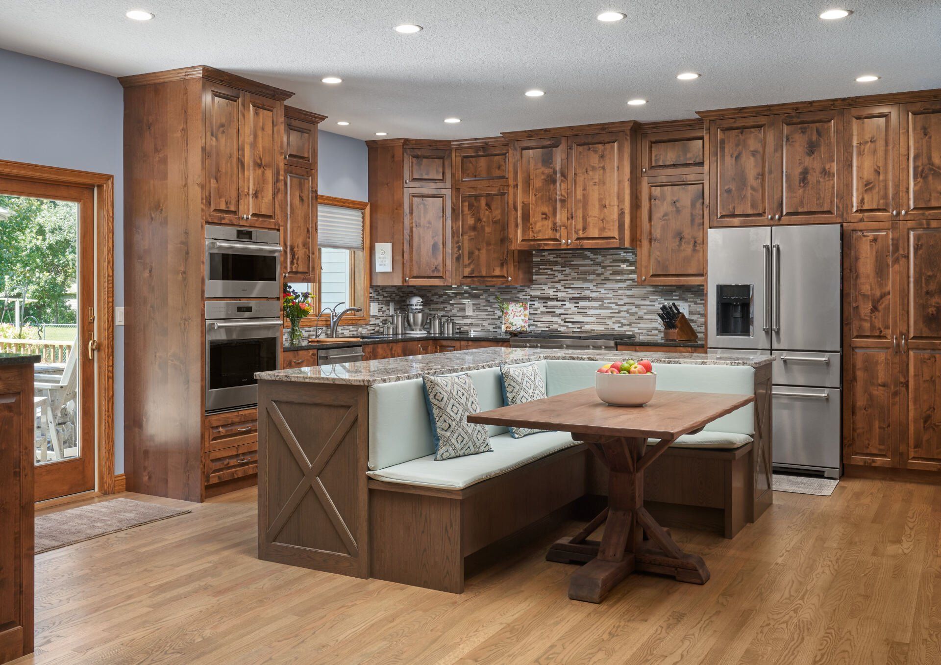 Custom kitchen remodeling project in Woodbury, MN with rustic wood cabinetry, built-in breakfast nook, and stone backsplash