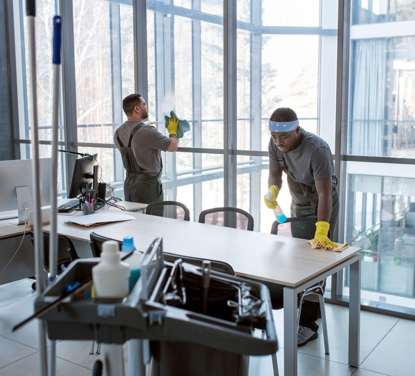 two men are cleaning a window in an office .