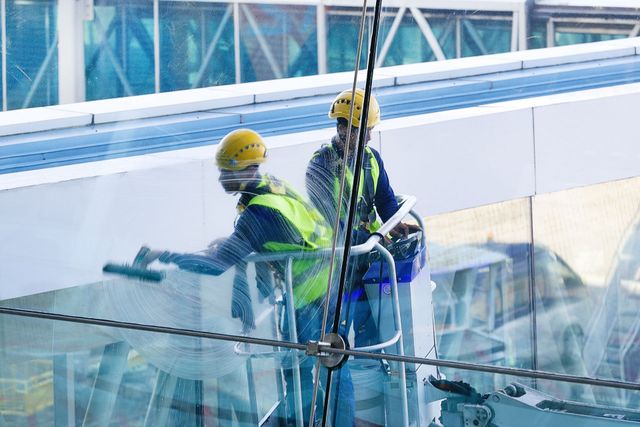 Two men are cleaning the windows of a building.