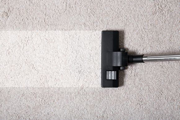 a vacuum cleaner is cleaning a white carpet .