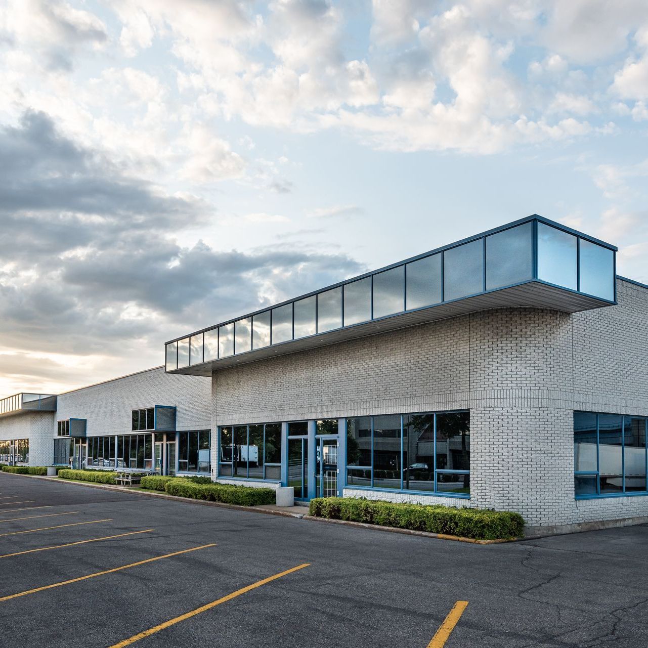 A large building with a lot of windows and a parking lot in front of it