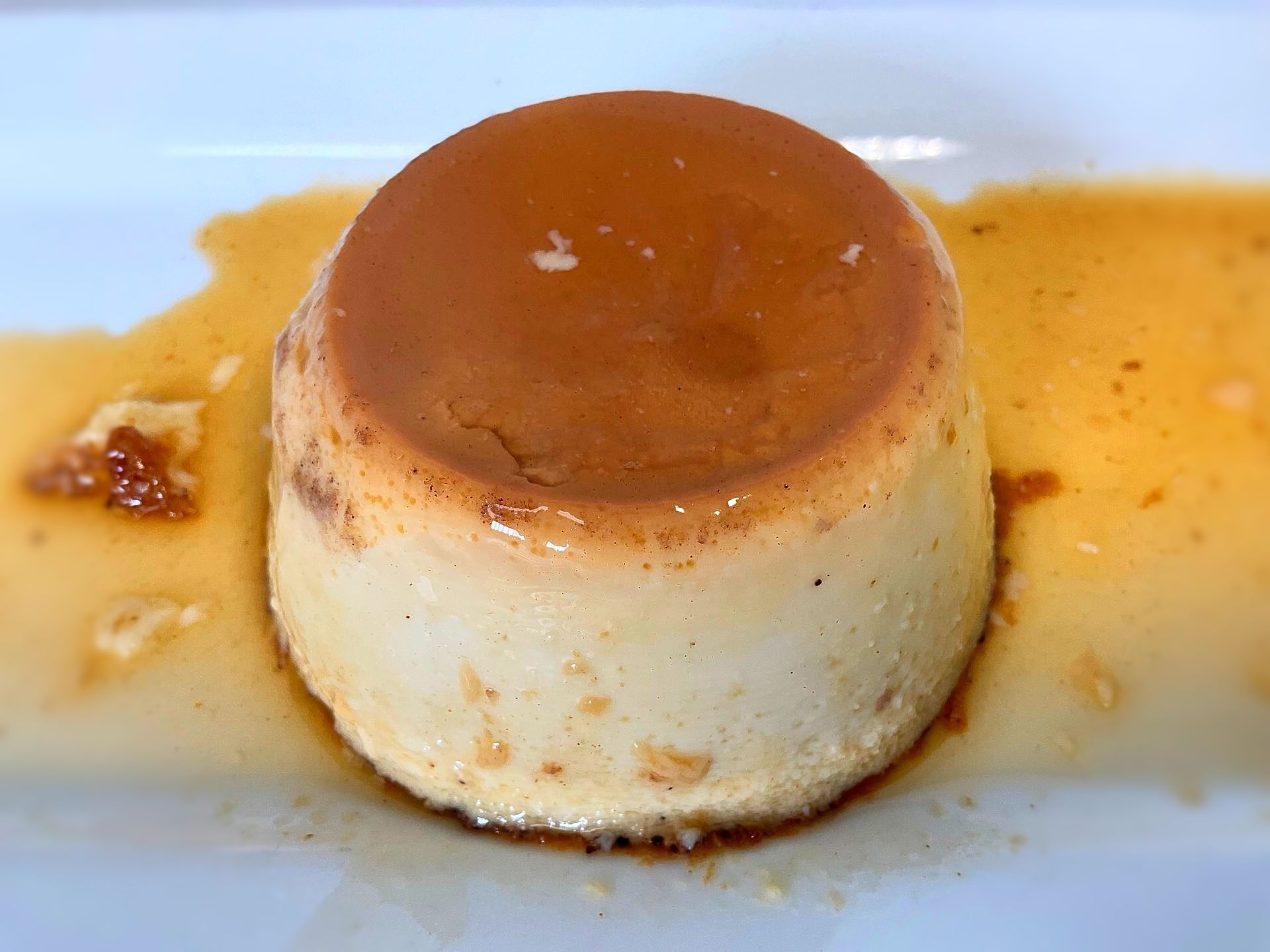 Custard dessert (flan) with caramel sauce on a white plate.