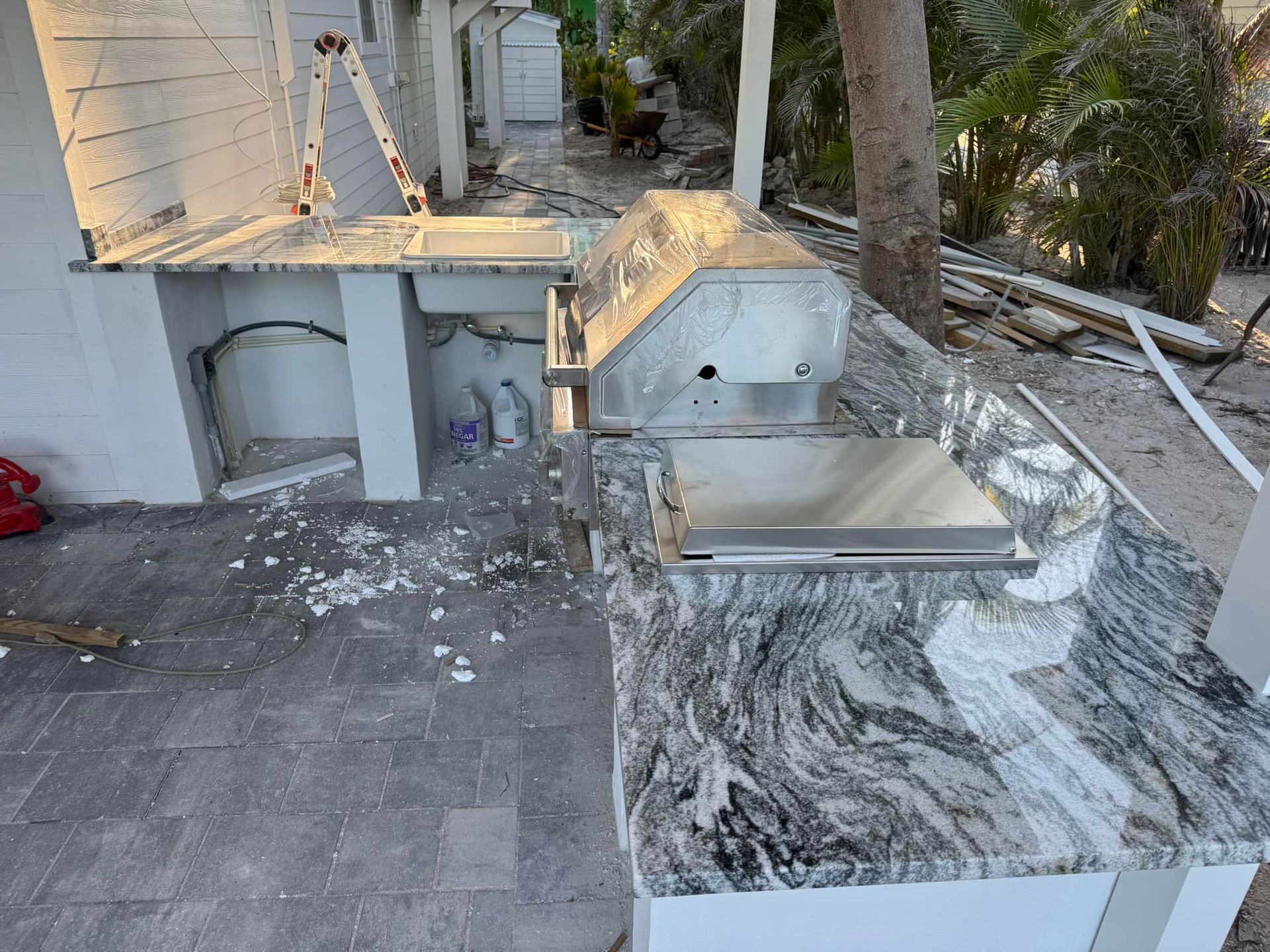 Damaged outdoor patio with shattered glass, broken stone countertop, and debris scattered across the floor