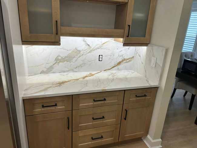 Built-in kitchen nook with white marble backsplash, quartz counter, and wood cabinets.