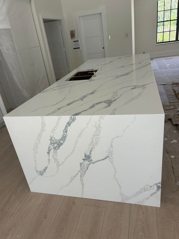 Modern white kitchen island with gray veining in a bright room