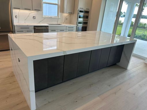 Modern kitchen island with white countertop and dark cabinet base in a bright home interior