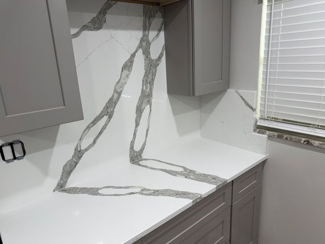 Modern kitchen with gray cabinets and white marble-look countertop and backsplash