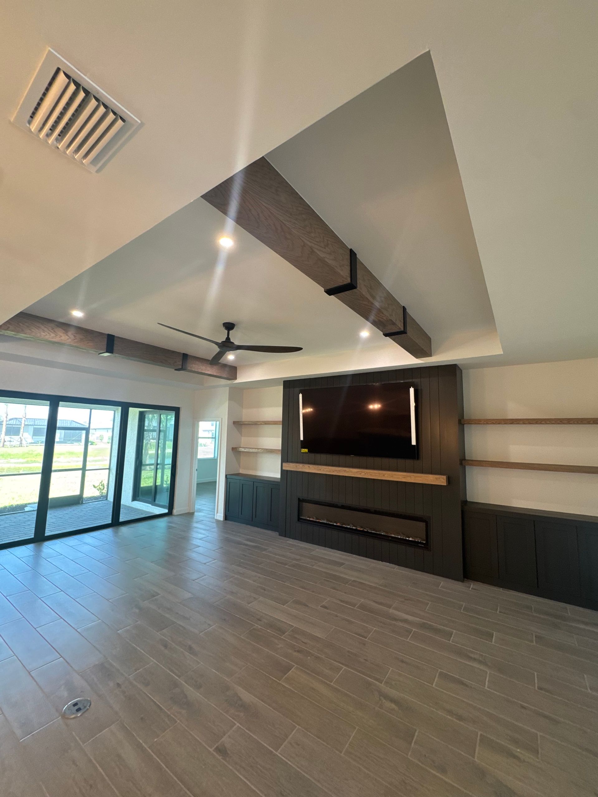 Modern living room with TV wall, fireplace, ceiling fan, and large glass sliding doors