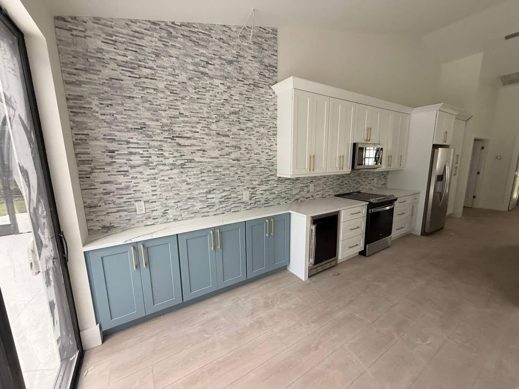 Modern kitchen with blue and white cabinets, patterned backsplash, and light wood flooring
