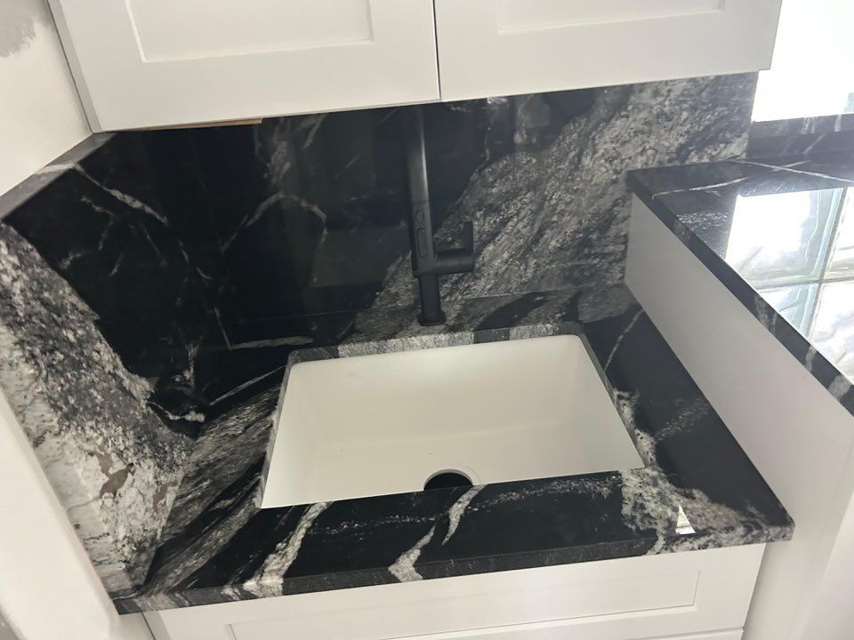 Black-and-white marble bathroom vanity with a white sink and black countertop, viewed from above