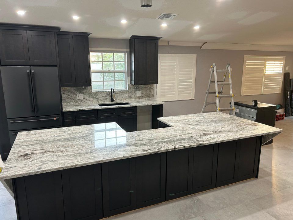 Modern kitchen with dark cabinets, white granite island, and two white bar stools