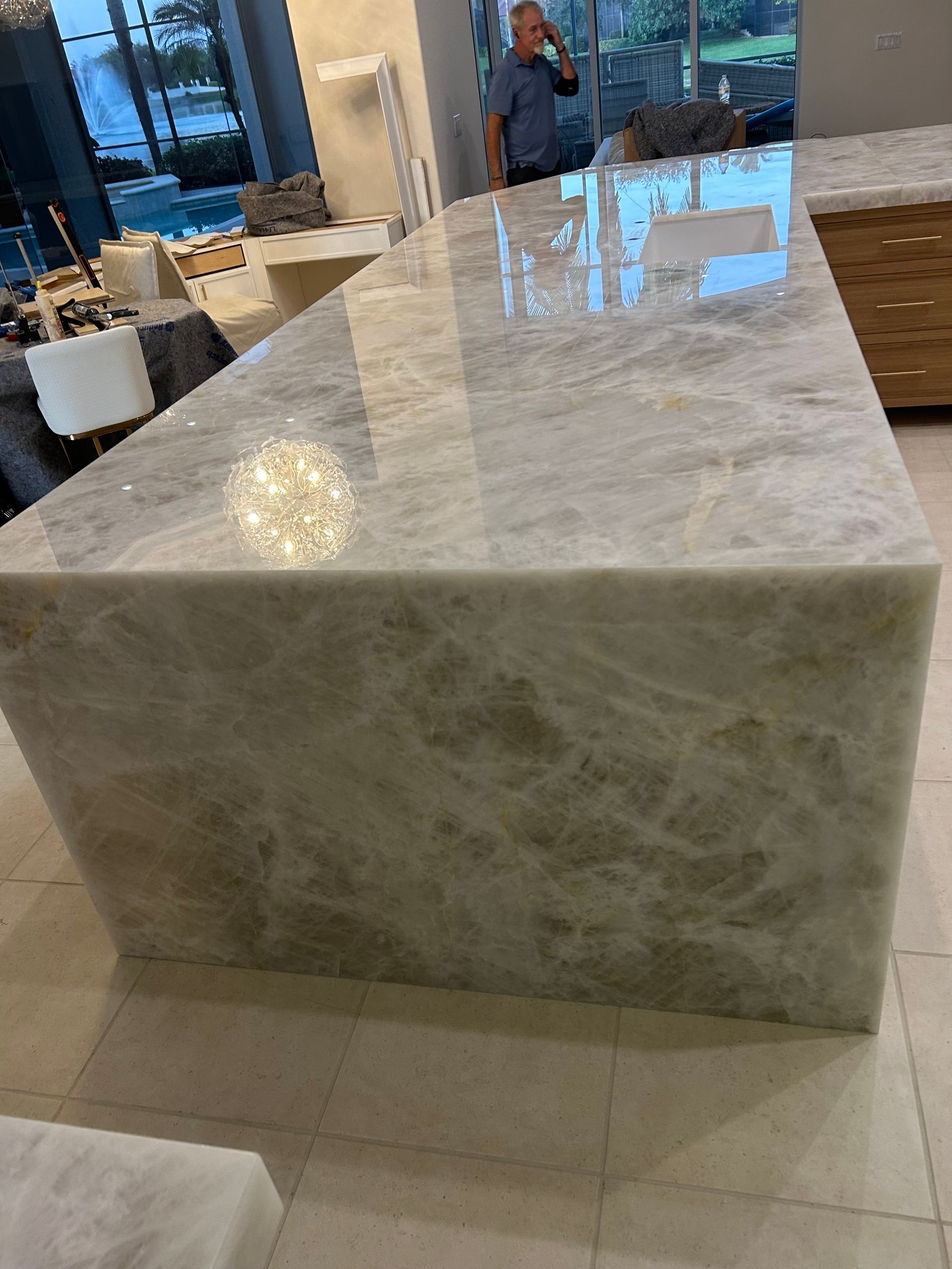 Large polished marble table in a modern showroom with floor-to-ceiling windows.
