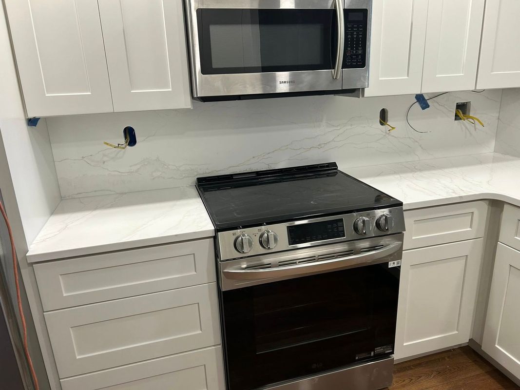 Modern white kitchen with stainless steel stove, microwave, cabinets, and countertops