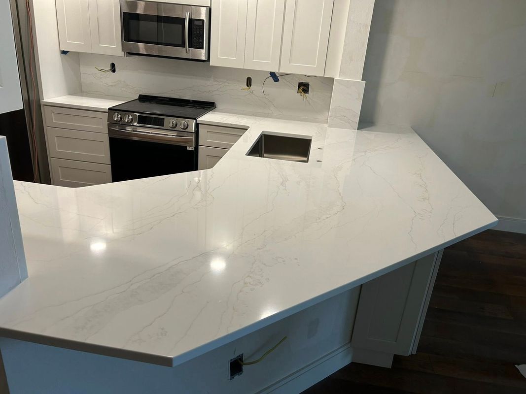 Modern kitchen with a large white countertop and stainless steel appliances