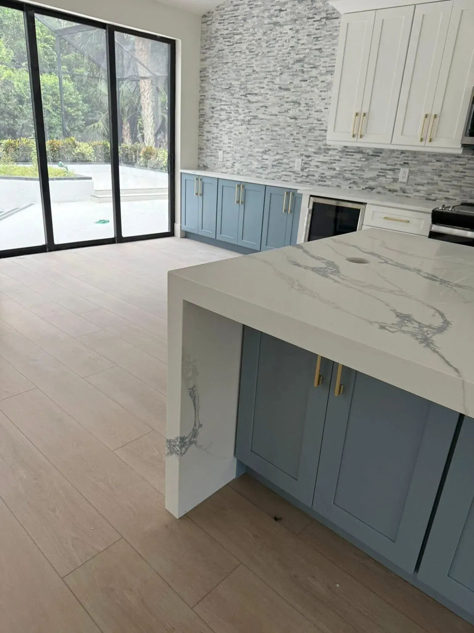 Bright kitchen with blue cabinets, white marble island, and large sliding glass doors to a patio