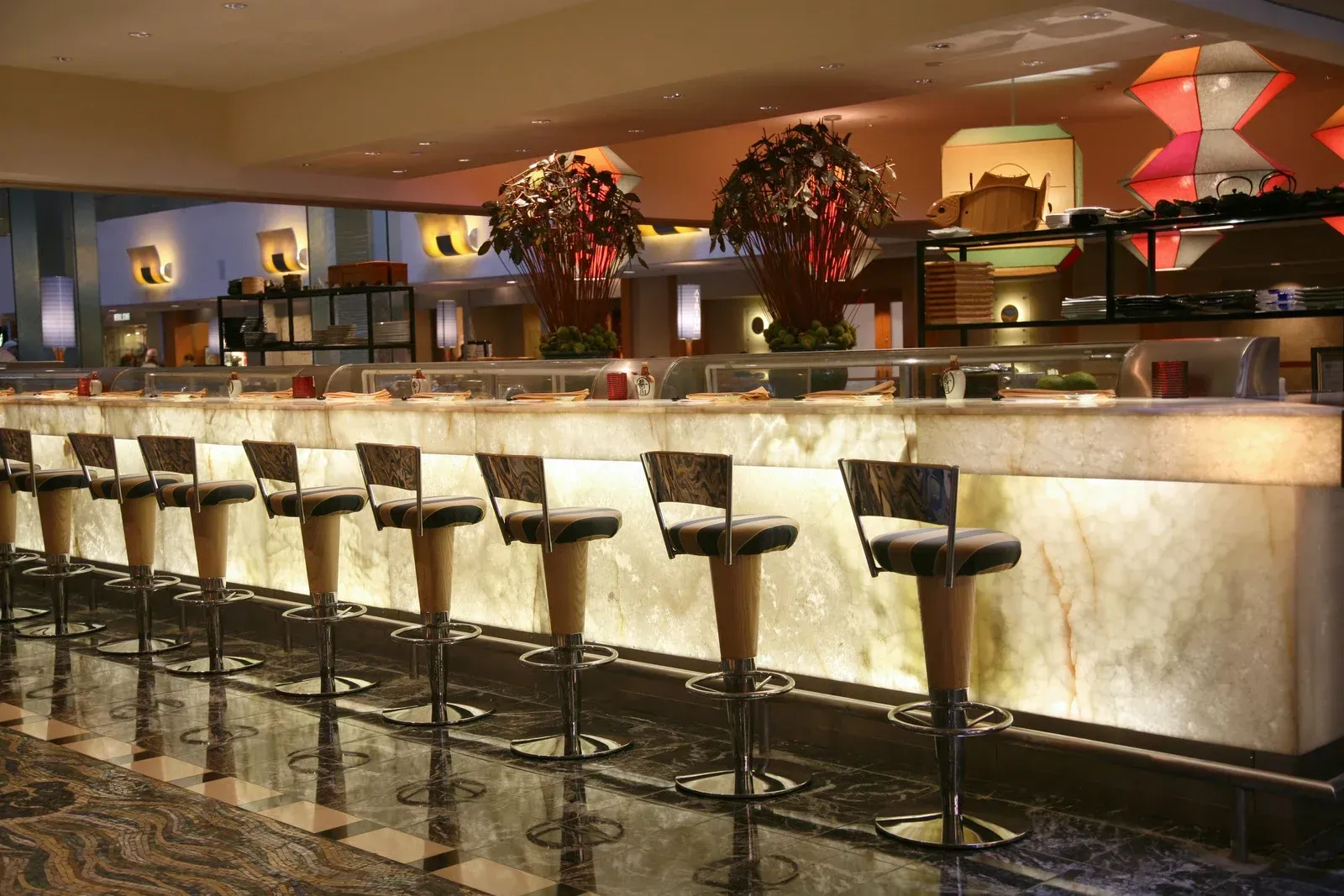 Modern bar interior with a long marble counter, tall stools, and warm ambient lighting