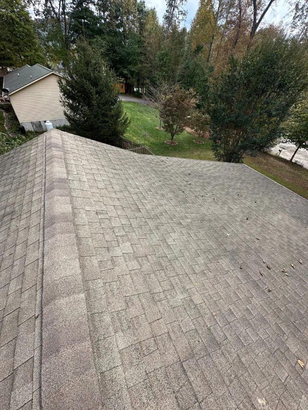 A roof with a lot of shingles on it and a house in the background.