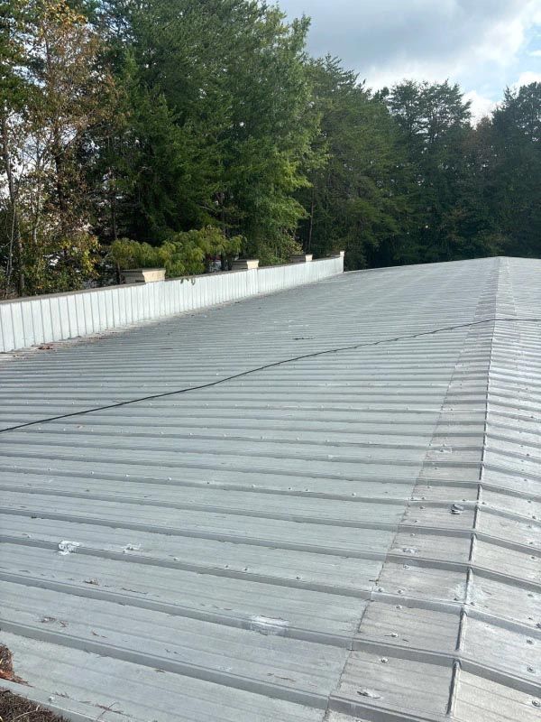 A large metal roof with trees in the background.