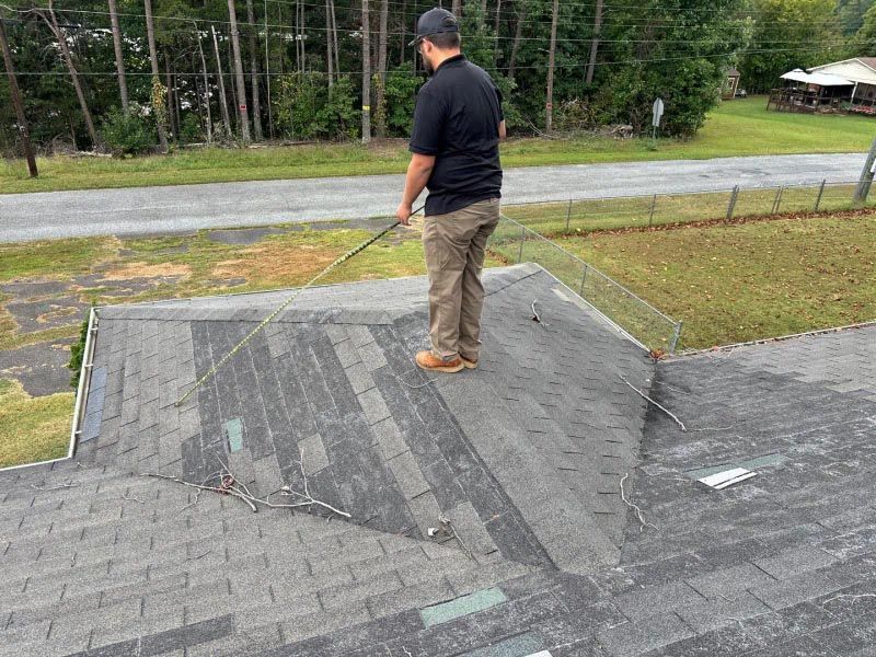 A man is standing on top of a roof with a hose.
