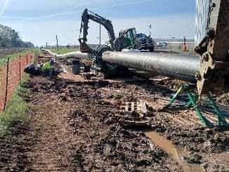 A large pipe is being installed on the side of a road.