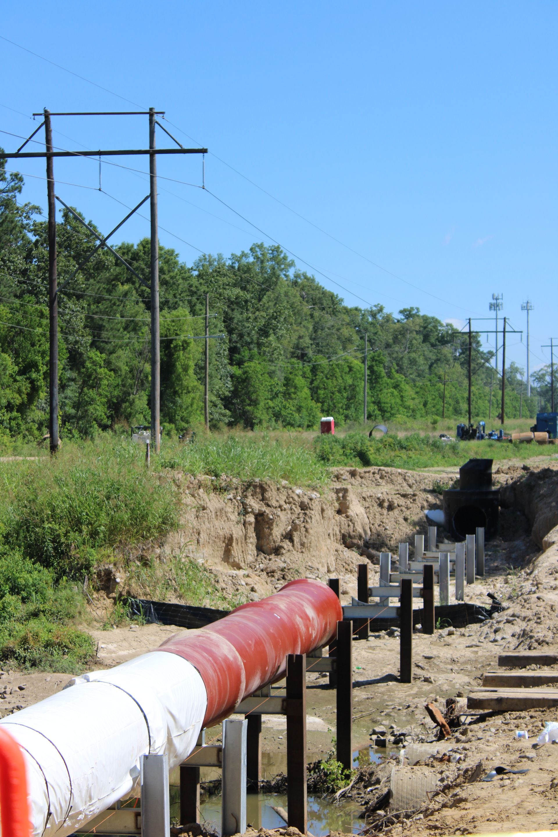 A yellow ladder is sitting in the dirt next to a blue pipe.
