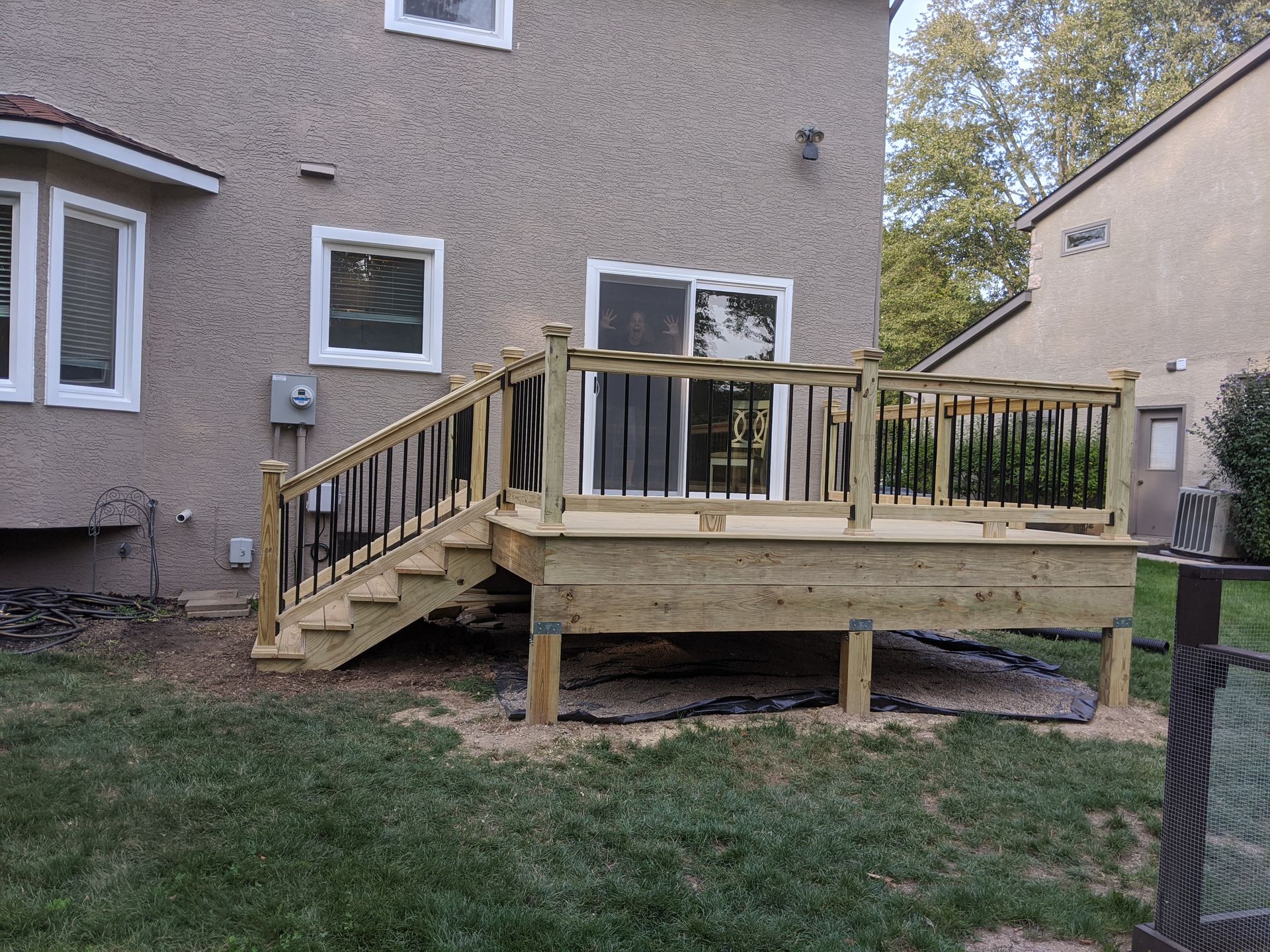 A wooden deck with stairs is in the backyard of a house.