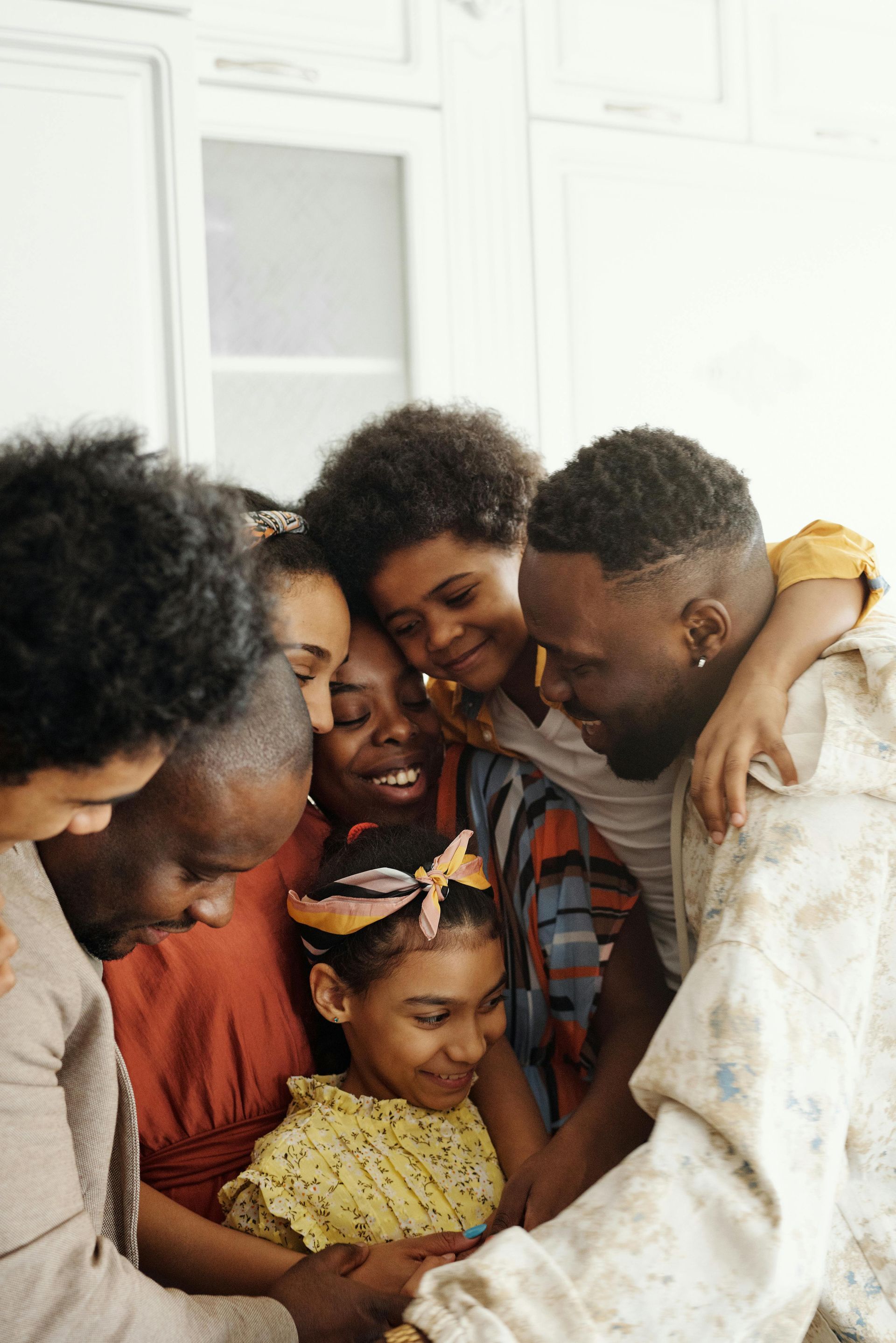 Family embracing, looking down at something together; happy expressions, bright setting.