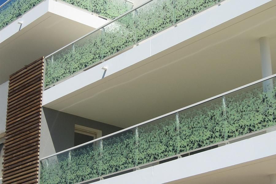 Balconies with green, decorative glass railings and white exterior.