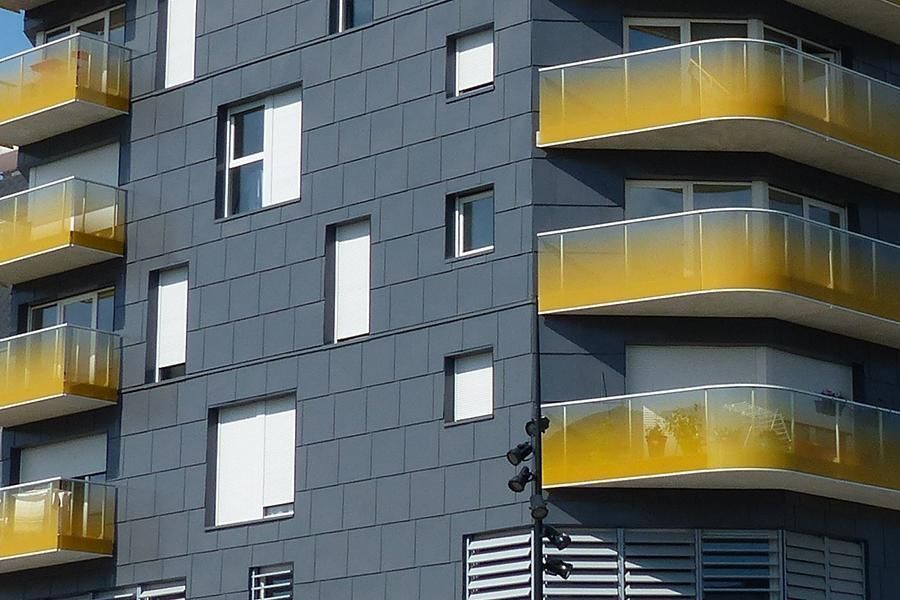 Dark gray building with yellow-tinted balconies; modern architectural design.