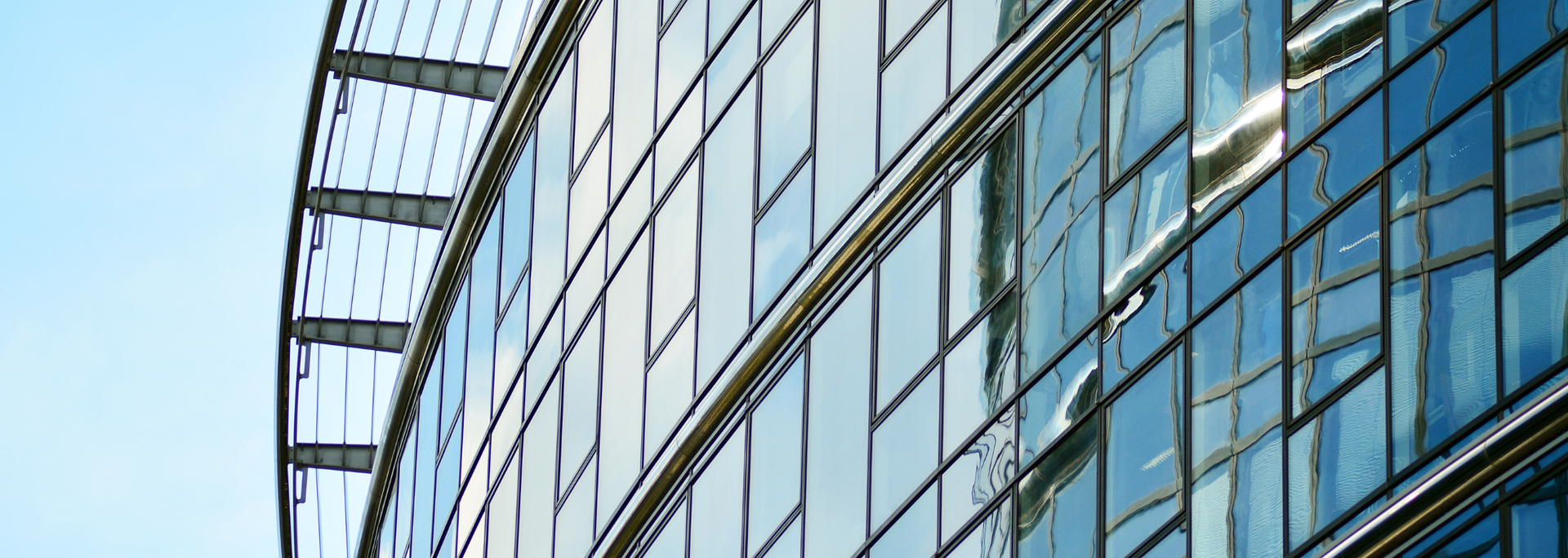 Glass-walled modern office building reflecting sky.