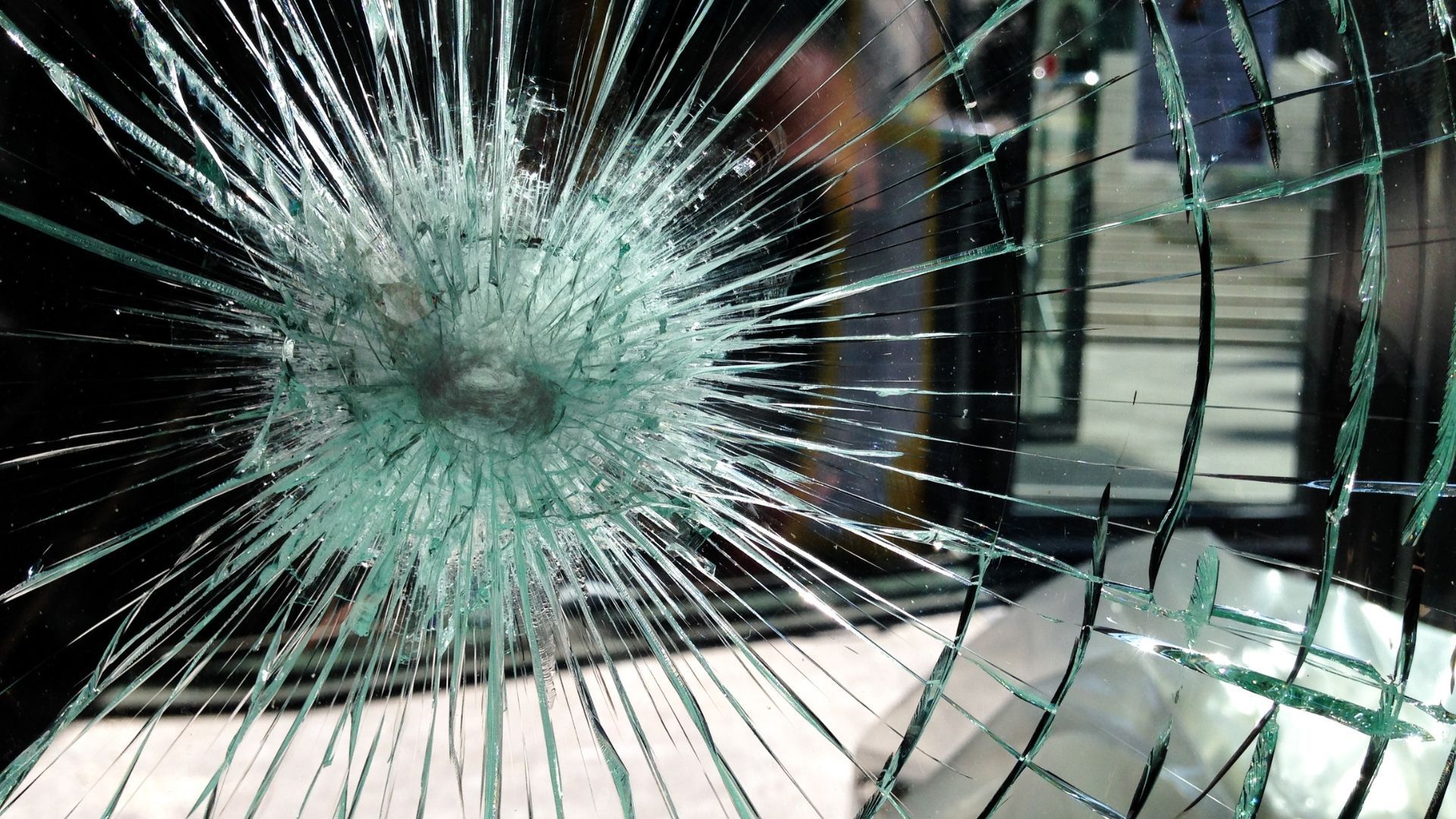 Shattered glass window with a central impact point and radiating cracks.