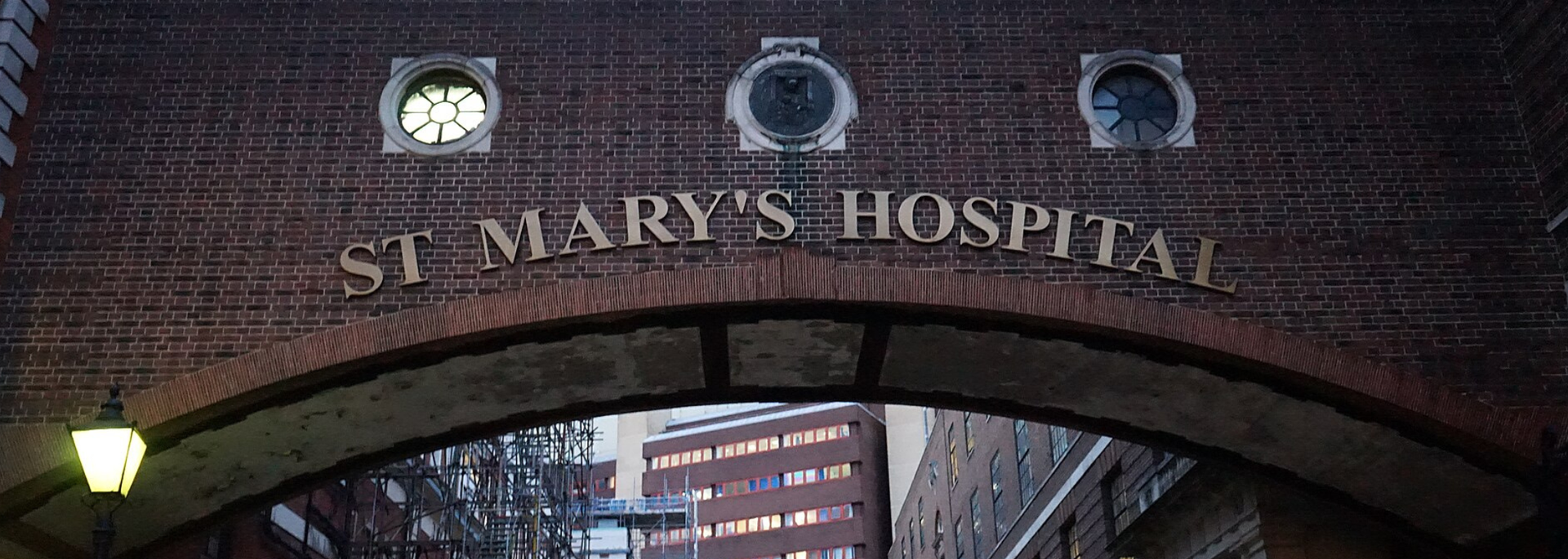 St. Mary's Hospital sign above an arched entrance with three small circular windows and an attached lamp.