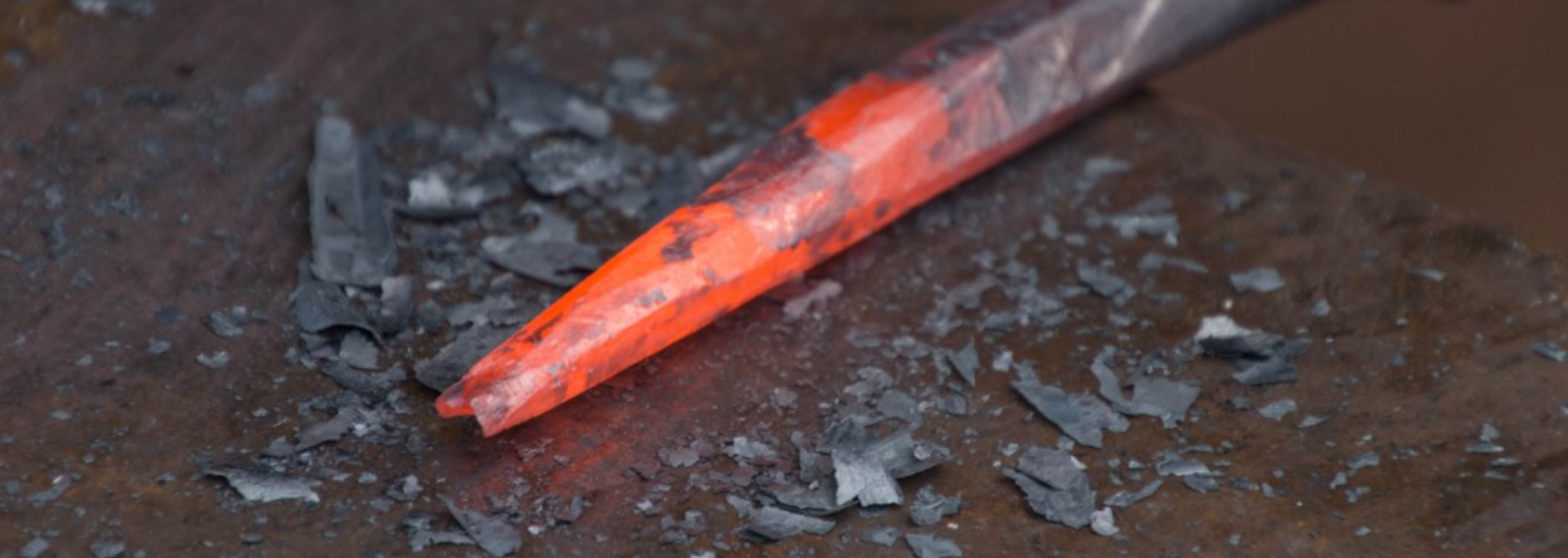 Glowing red metal tool on a dark surface, surrounded by dark debris.