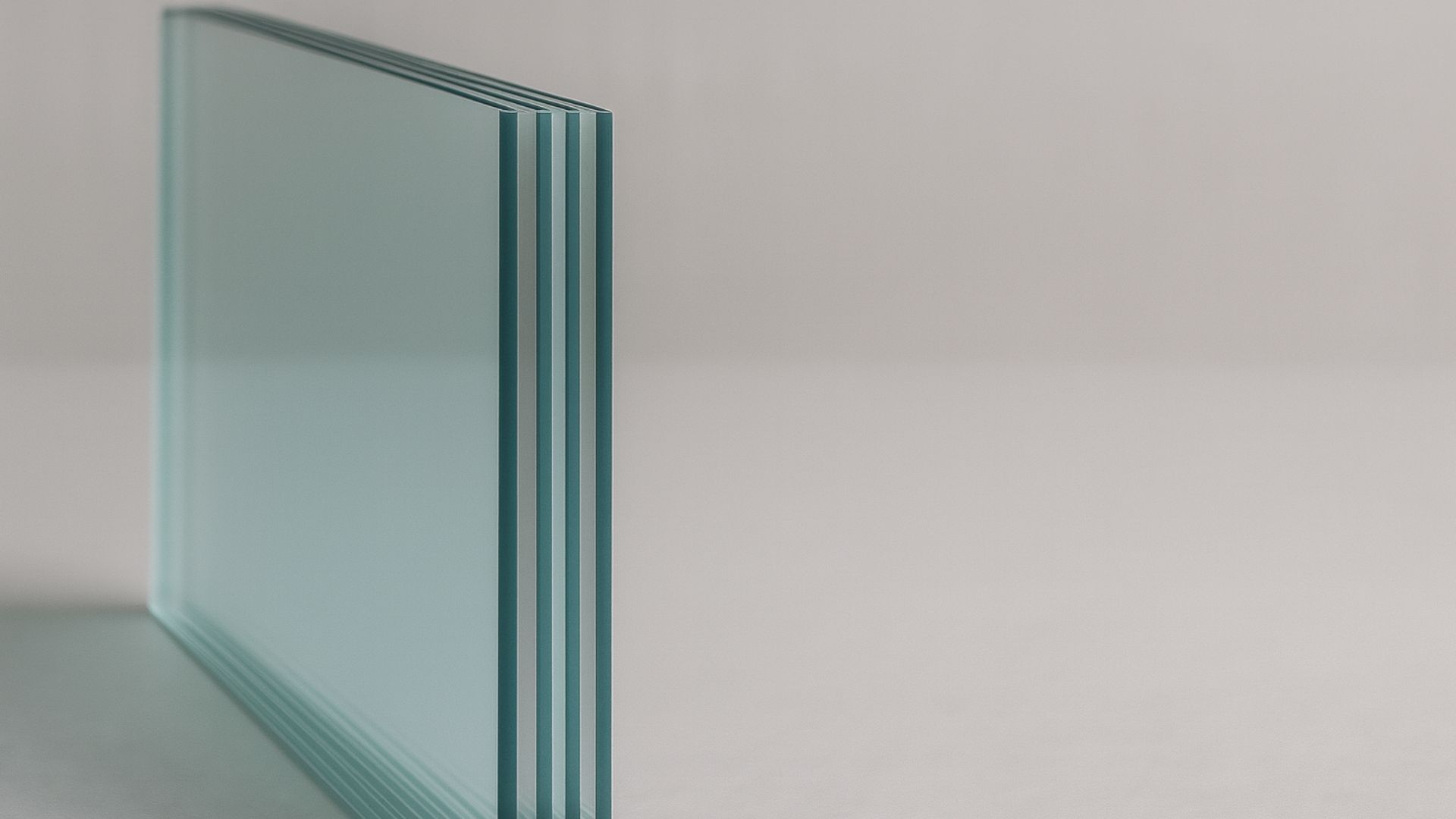 Stack of clear glass panels on a white surface, side view.